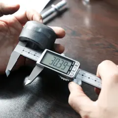 Precyzyjna budowa mikrometru: dłonie trzymają suwmiarkę cyfrową, mierzącą element o średnicy 30.39 mm.