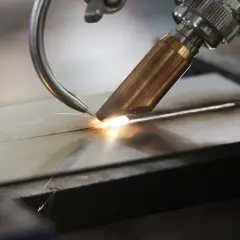 Precyzyjne spawanie laserowe aluminium, tworzące idealne połączenie dwóch elementów. Iskry i jasny łuk świadczą o wysokiej temperaturze procesu.
